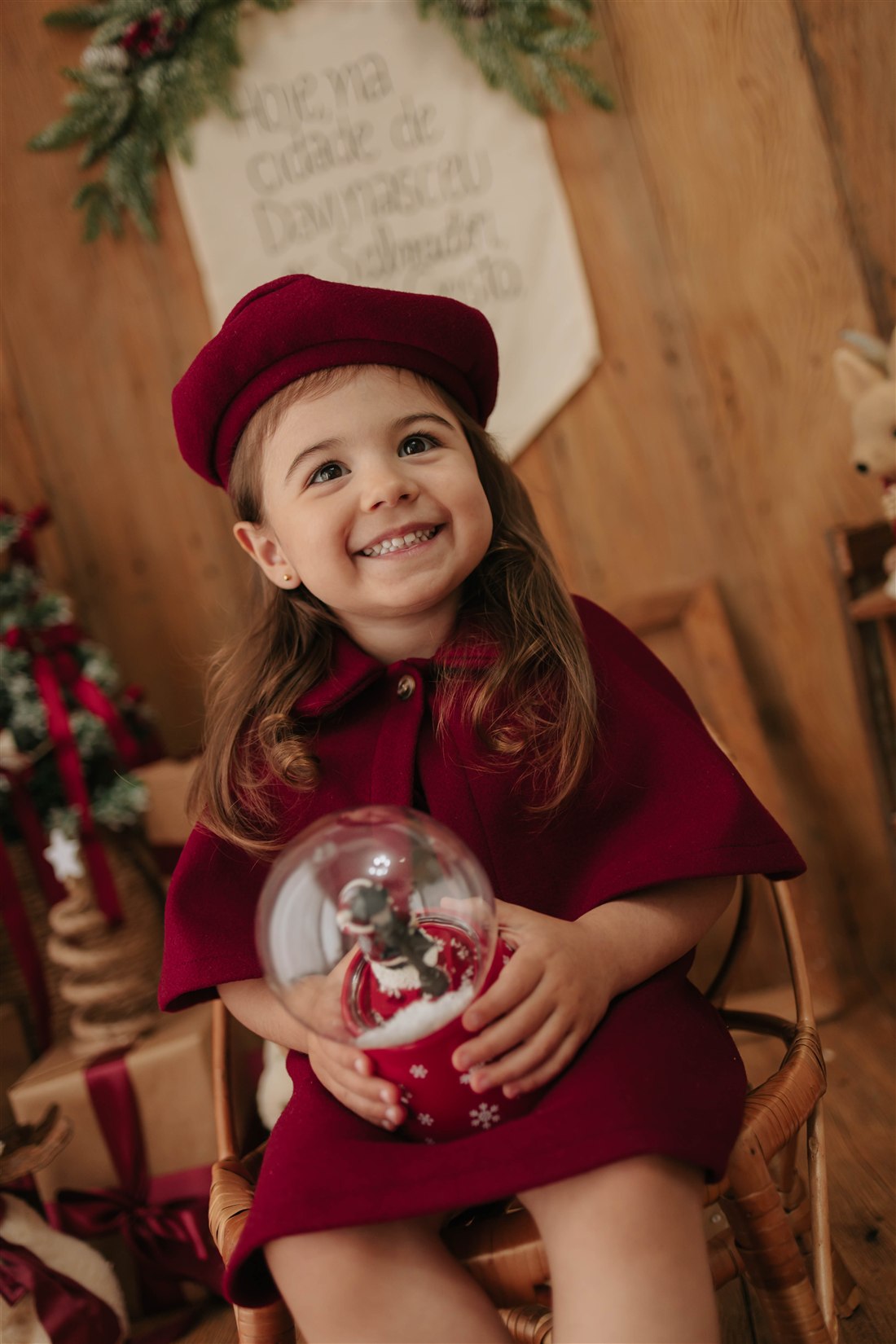 Menina de boina e roupa vermelha segurando um globo de neve